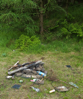 An illegal campfire surrounded by rubbish.
